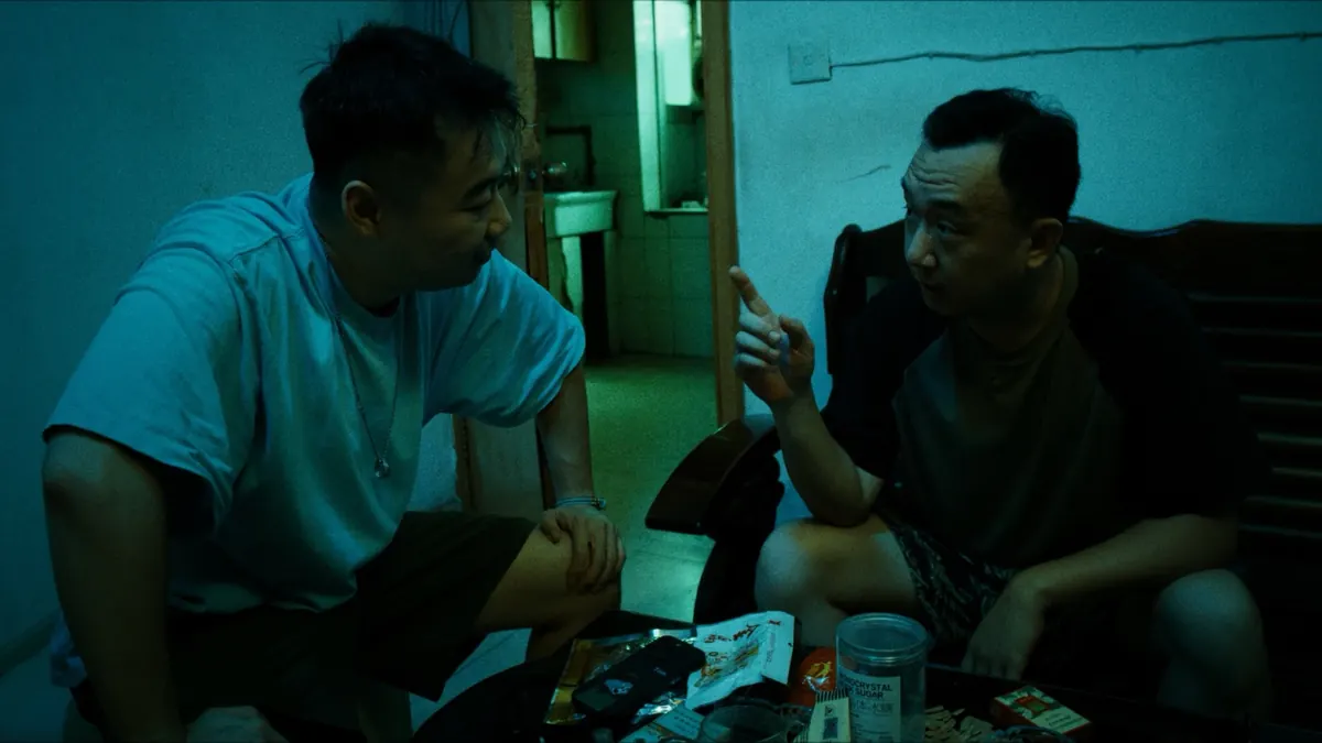 Two men talking in a dimly lit room